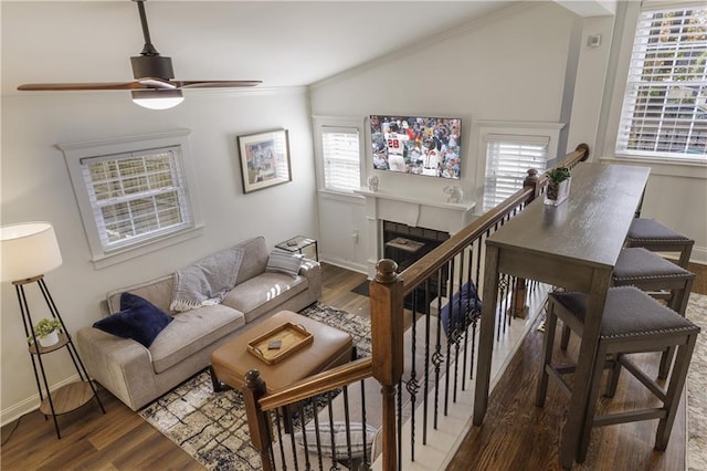 living room featuring a tiled fireplace, baseboards, vaulted ceiling, and wood finished floors