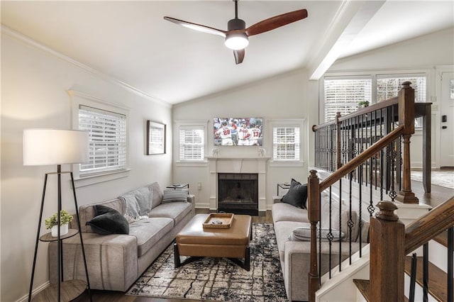 living room with crown molding, a fireplace, vaulted ceiling, ceiling fan, and wood finished floors