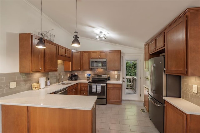 kitchen with light countertops, appliances with stainless steel finishes, vaulted ceiling, a sink, and a peninsula