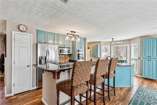 kitchen featuring a kitchen breakfast bar, stainless steel appliances, and wood finished floors