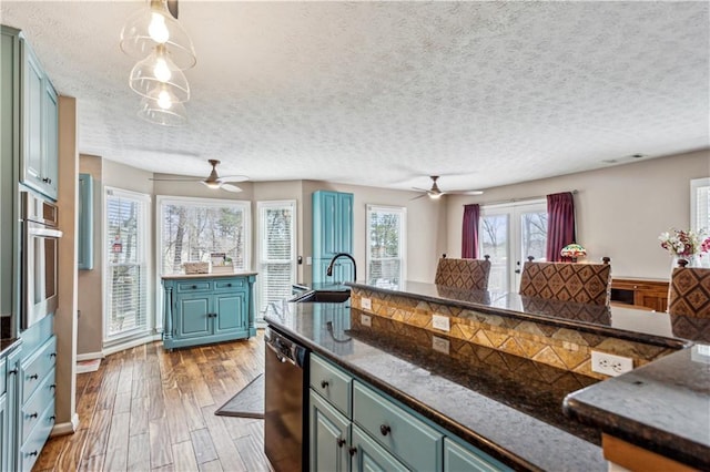 kitchen with stainless steel oven, wood finished floors, black dishwasher, and ceiling fan