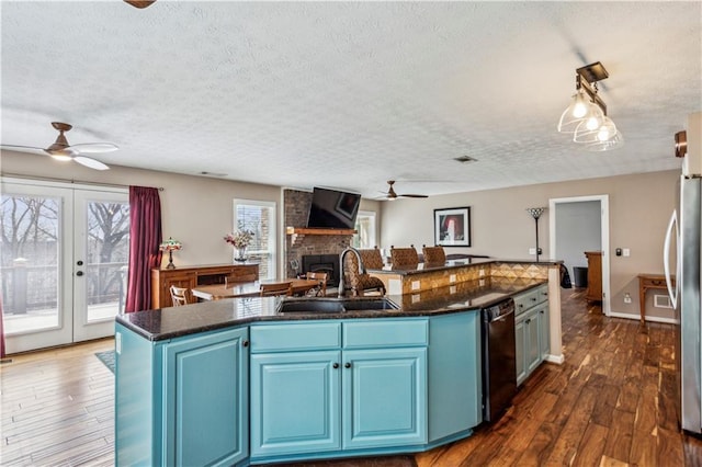 kitchen with a fireplace, blue cabinetry, a ceiling fan, and a sink