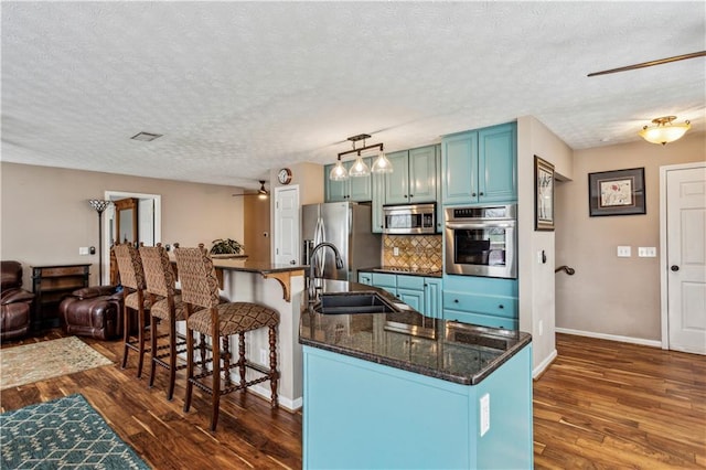 kitchen featuring a sink, a breakfast bar, dark wood-style floors, and stainless steel appliances