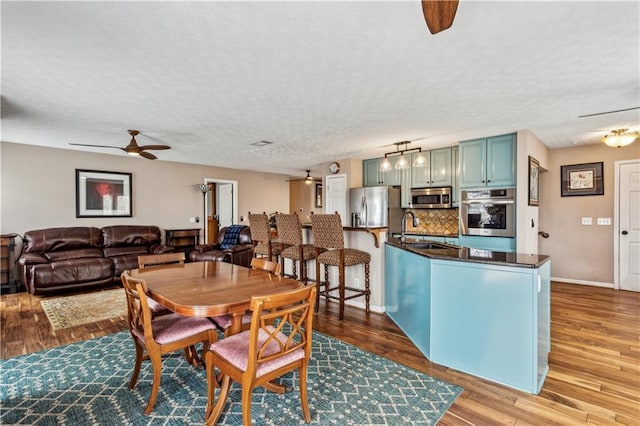 dining area with a textured ceiling, wood finished floors, baseboards, and ceiling fan