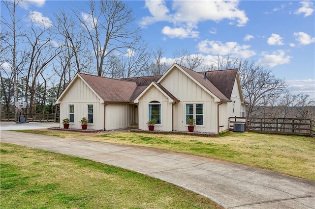 view of front of home with fence, roof with shingles, a front lawn, concrete driveway, and board and batten siding