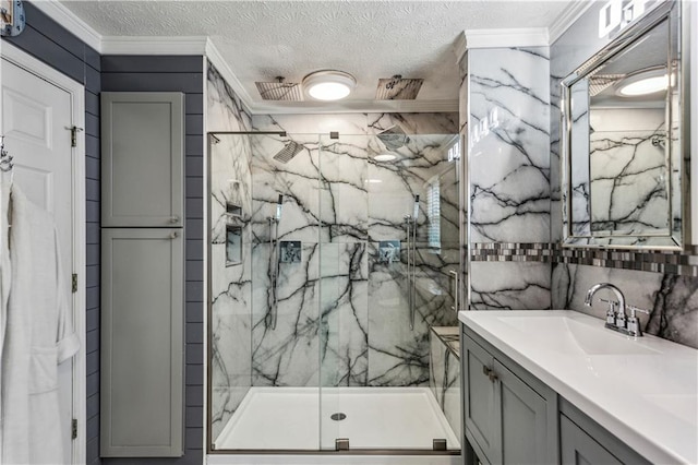 bathroom featuring a marble finish shower, crown molding, a textured ceiling, and vanity