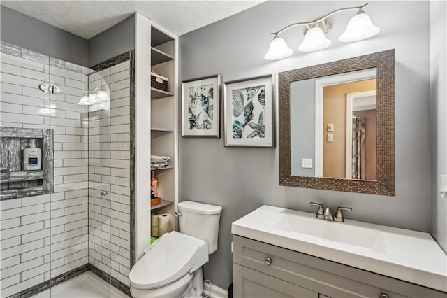 full bathroom featuring vanity, toilet, a tile shower, and a textured ceiling