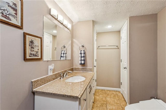 bathroom featuring tile patterned flooring, baseboards, toilet, vanity, and a textured ceiling