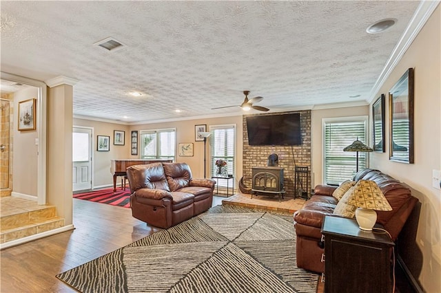 living area featuring a wealth of natural light, visible vents, a wood stove, and wood finished floors