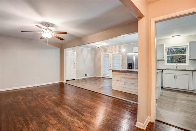 unfurnished living room with ceiling fan, dark hardwood / wood-style flooring, and sink