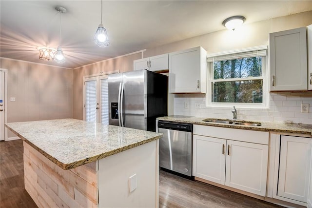 kitchen with tasteful backsplash, stainless steel appliances, sink, white cabinetry, and a kitchen island