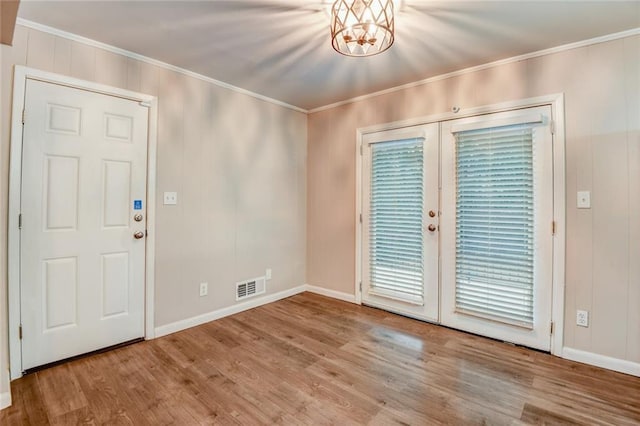 interior space with light wood-type flooring, crown molding, and an inviting chandelier