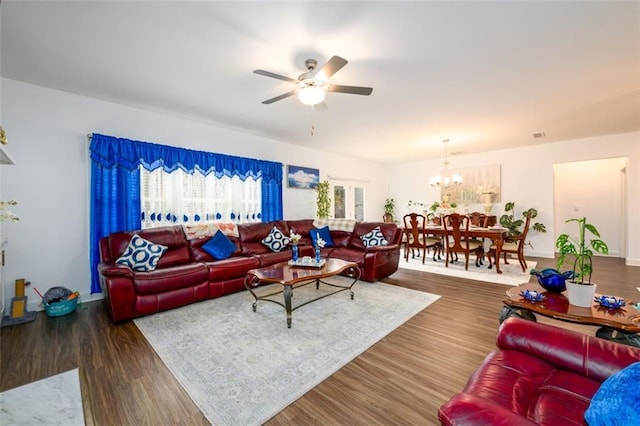 living room featuring ceiling fan with notable chandelier and dark wood-type flooring