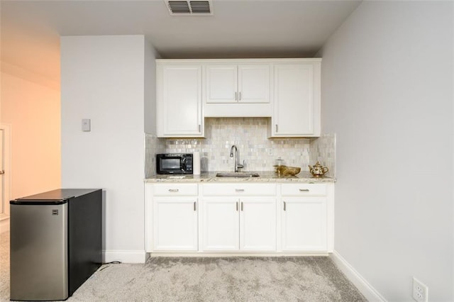 kitchen with white cabinets, stainless steel fridge, light colored carpet, and sink