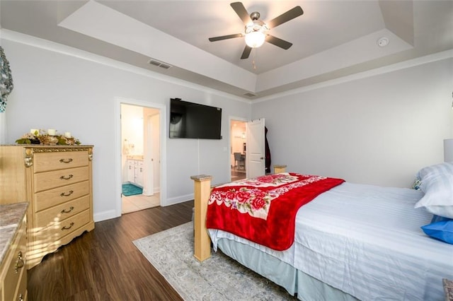 bedroom with ensuite bath, ceiling fan, dark wood-type flooring, and a tray ceiling