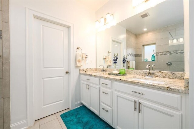 bathroom with tile patterned floors, vanity, and tiled shower