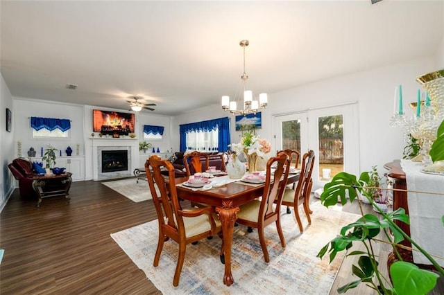 dining space featuring french doors, ceiling fan with notable chandelier, dark wood-type flooring, and a healthy amount of sunlight