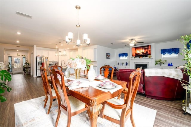 dining room featuring sink, ceiling fan with notable chandelier, and light wood-type flooring