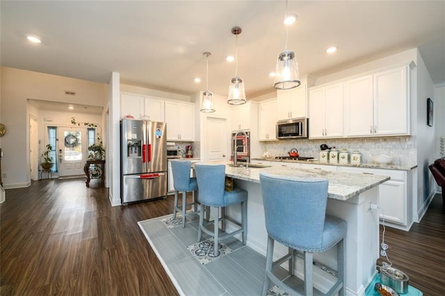 kitchen with white cabinetry, stainless steel appliances, and an island with sink