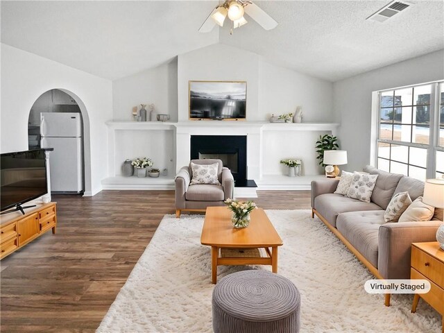 unfurnished living room with dark hardwood / wood-style flooring, a textured ceiling, vaulted ceiling, and ceiling fan