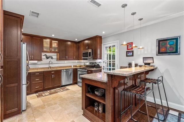 kitchen featuring light stone counters, sink, kitchen peninsula, hanging light fixtures, and appliances with stainless steel finishes