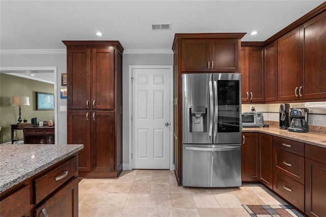 kitchen with light stone countertops, stainless steel fridge, and crown molding