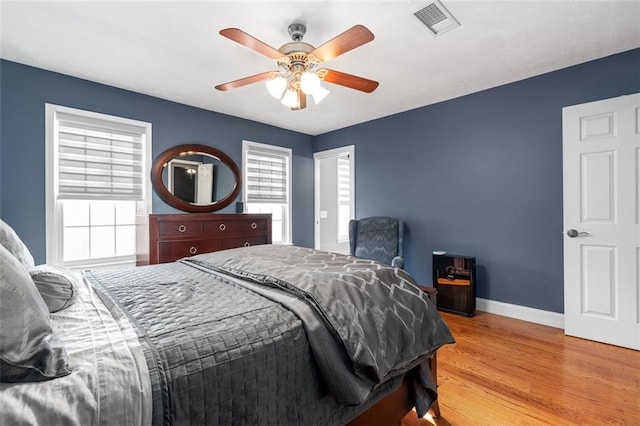 bedroom with light wood-type flooring, ceiling fan, and multiple windows