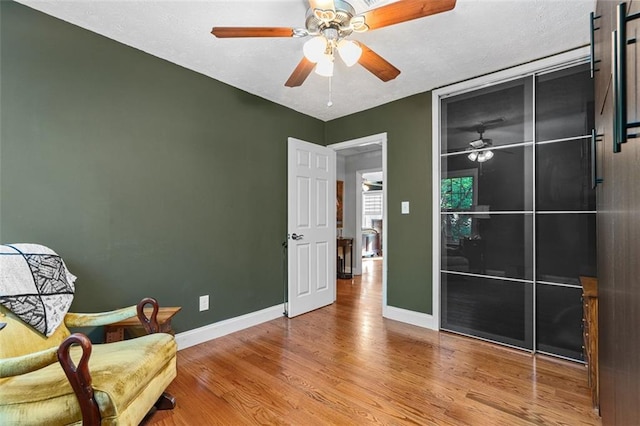 living area with wood-type flooring and ceiling fan