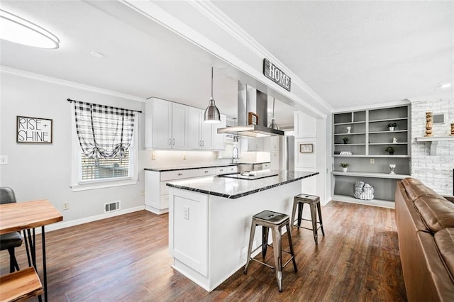 kitchen featuring crown molding, a breakfast bar area, a center island, white cabinets, and island exhaust hood