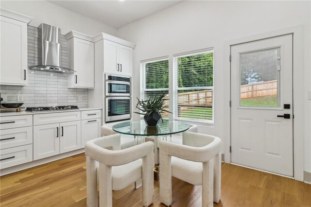 1129 Victory Dr SW, Atlanta, GA 30310 - kitchen with wall chimney exhaust hood, gas cooktop, double oven, decorative backsplash, and white cabinetry