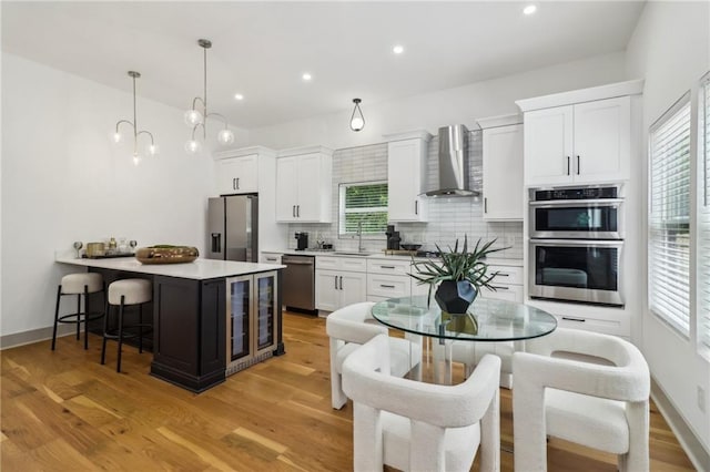 1129 Victory Dr SW, Atlanta, GA 30310 - kitchen with appliances with stainless steel finishes, wall chimney range hood, a kitchen bar, backsplash, and white cabinets