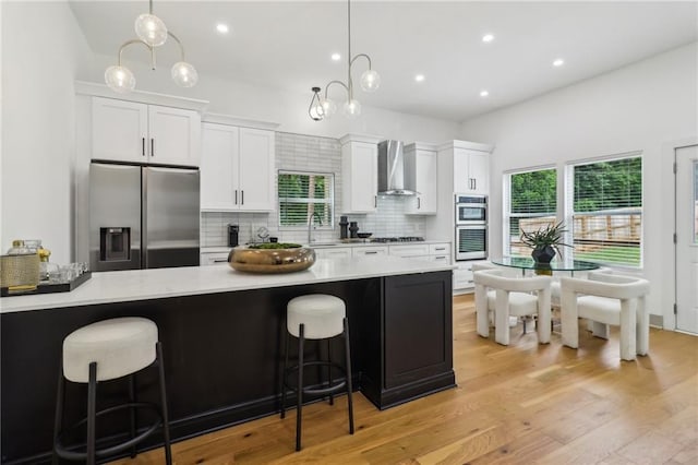 1129 Victory Dr SW, Atlanta, GA 30310 - kitchen featuring appliances with stainless steel finishes, wall chimney range hood, backsplash, white cabinets, and light countertops