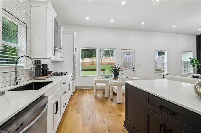 1129 Victory Dr SW, Atlanta, GA 30310 - kitchen with a sink, appliances with stainless steel finishes, white cabinets, backsplash, and light wood-style flooring