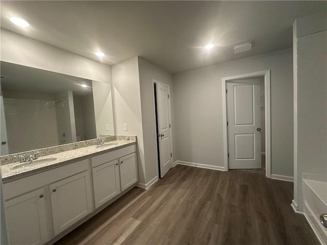75 Emerald Ln, Covington, GA 30014 - bathroom featuring wood finished floors, double vanity, baseboards, a tub, and recessed lighting