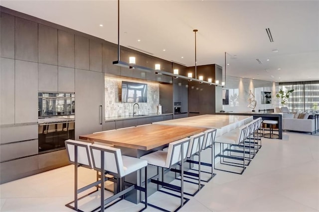 kitchen featuring a kitchen bar, wood counters, hanging light fixtures, sink, and double oven