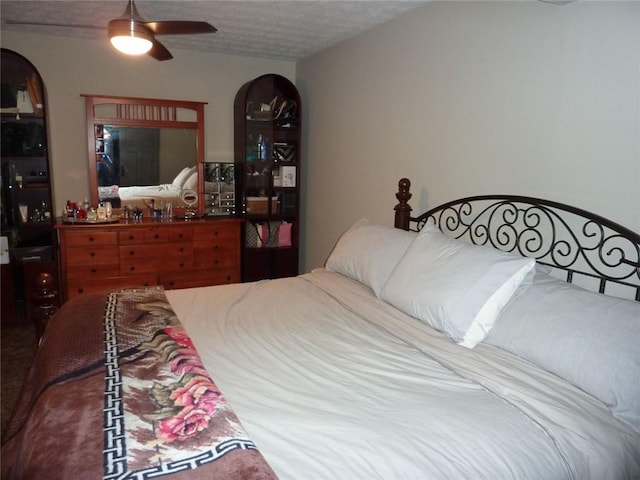 bedroom featuring arched walkways, ceiling fan, and a textured ceiling