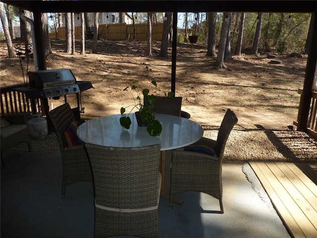 view of patio featuring outdoor dining space, fence, and a grill