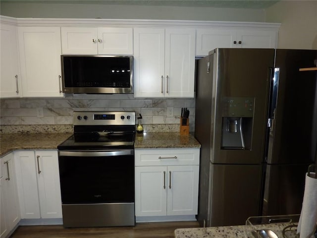 kitchen with white cabinets, tasteful backsplash, refrigerator with ice dispenser, and stainless steel range with electric cooktop