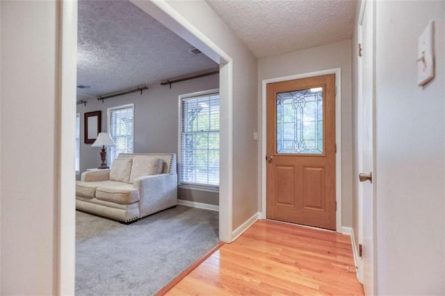 entrance foyer featuring a textured ceiling, light wood-type flooring, visible vents, and baseboards