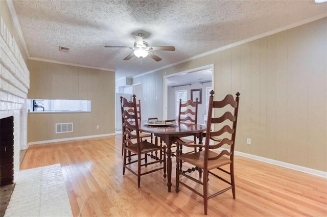 dining space featuring light wood-style floors, visible vents, and a fireplace