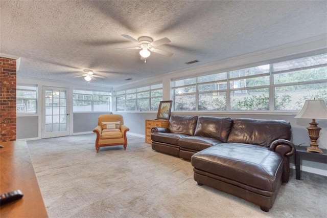 carpeted living room featuring a textured ceiling, baseboards, visible vents, and a ceiling fan