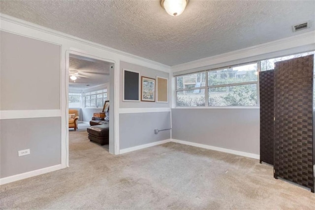 spare room featuring carpet, visible vents, crown molding, and baseboards