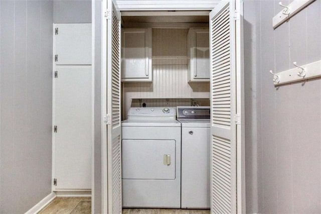 washroom with cabinet space, baseboards, and washing machine and clothes dryer