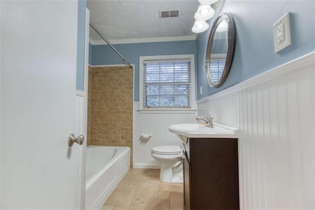 bathroom with a textured ceiling, toilet, vanity, visible vents, and wainscoting