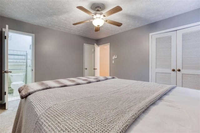 bedroom featuring a textured ceiling, light carpet, a ceiling fan, a closet, and ensuite bath