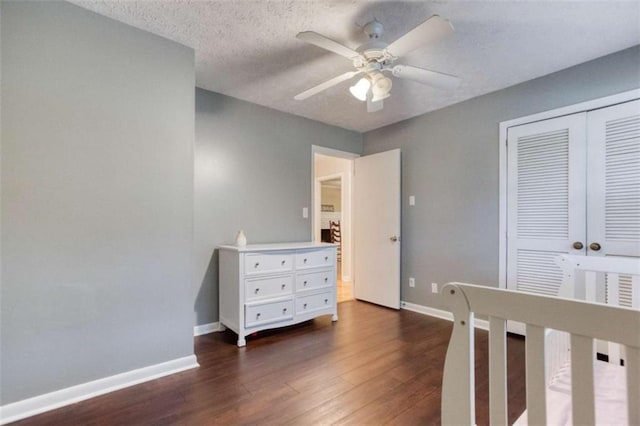 bedroom with a textured ceiling, baseboards, dark wood finished floors, and a closet