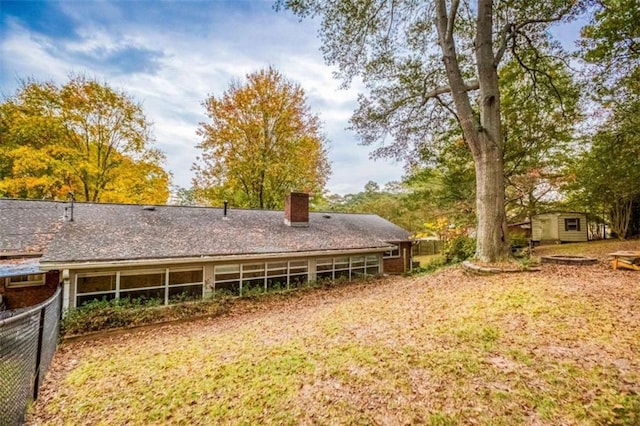 back of property with an outbuilding, a chimney, and fence