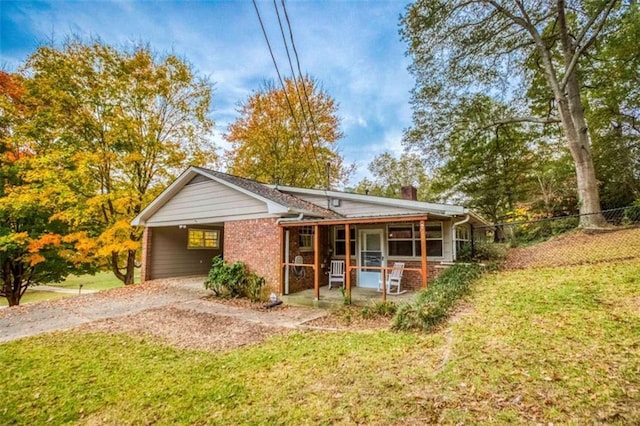 view of front facade with a chimney, fence, an attached carport, driveway, and a front lawn