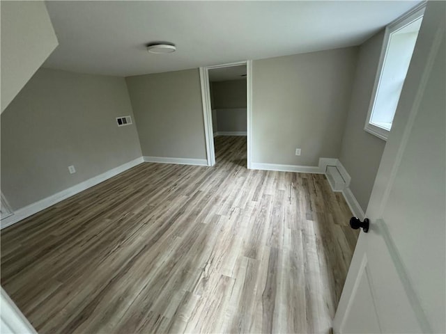 unfurnished bedroom with a spacious closet, baseboards, visible vents, and wood finished floors