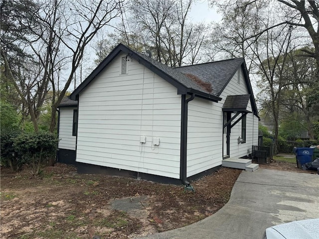 view of side of home with roof with shingles